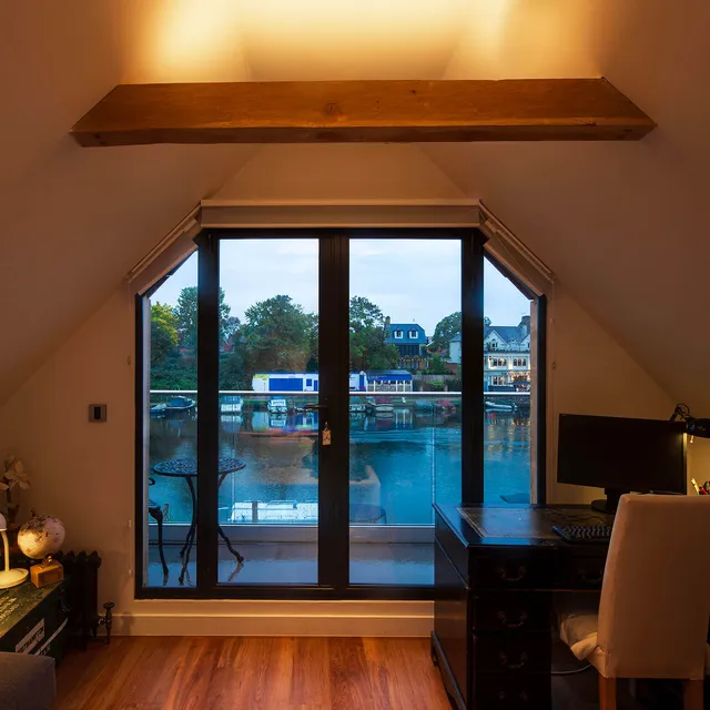 An uplit beamed ceiling in a small study looking out over the Thames