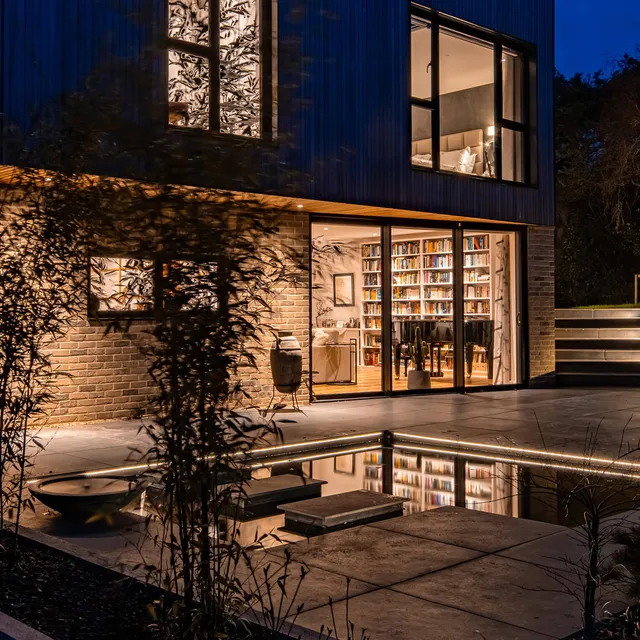Subtle downlighting and LED linear light framing the pool in New Forest garden lighting design