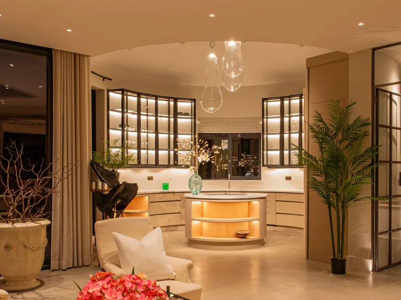 A stunning circular kitchen with lit shelving and oversize pendants over the island