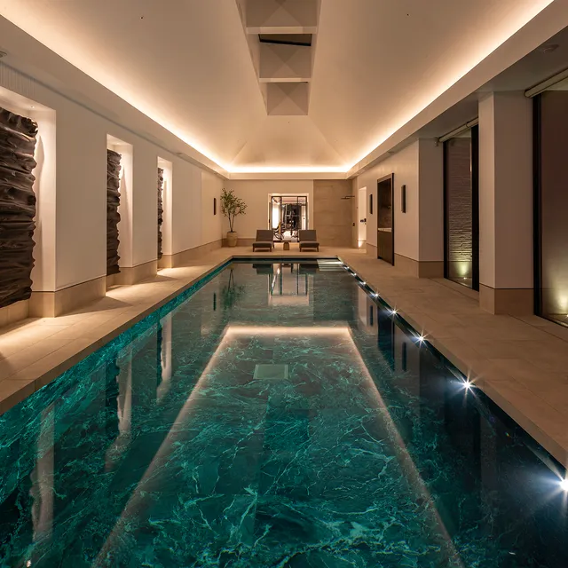 A beautifully tiled swimming pool with coffer lighting in a pitched ceiling