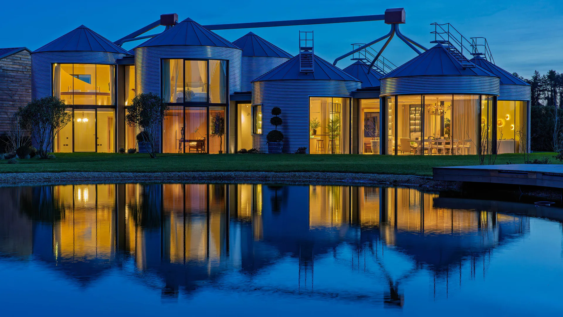 Evening shot of a luxury country house built around an array of agricultural silos