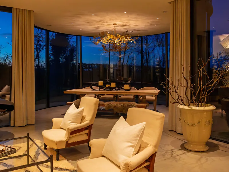 A circular dining room in a converted agricultural silo with decorative lighting and electric Lutron curtain tracks