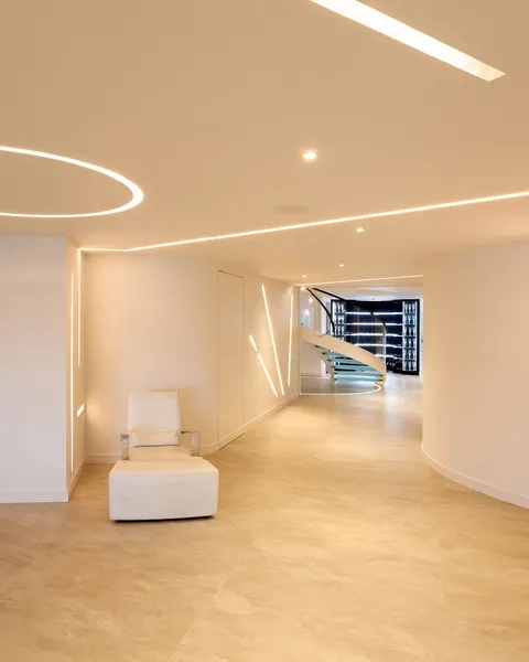 A helical staircase and basement lit with recessed linear LED lighting